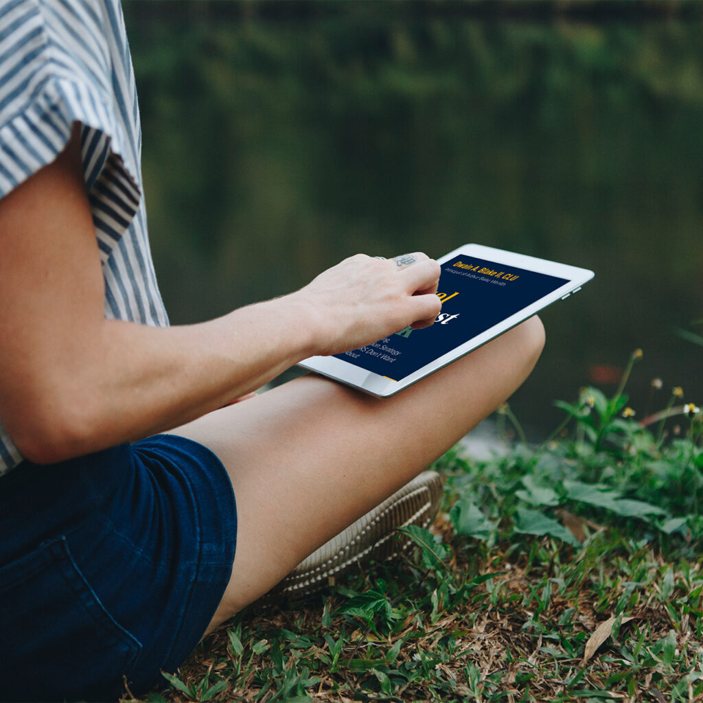 A person sitting on the grass with a tablet.